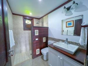 a bathroom with a sink and a toilet and a mirror at Santosha Barbados in Saint Andrew