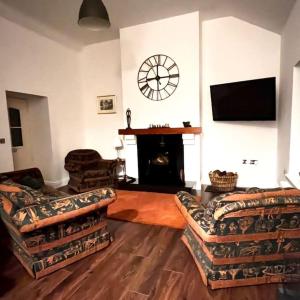 - un salon avec deux canapés et une horloge murale dans l'établissement Rectory Cottage. Close to Enniskillen and lakes., à Enniskillen