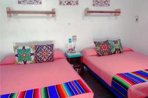 two beds in a room with colorful sheets and pillows at Beautiful & Cozy Studio in Akumal Paradise-Wifi, AC in Akumal