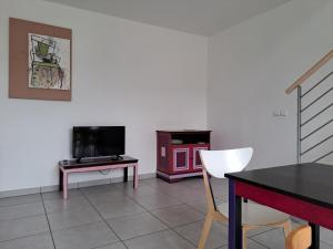 ein Wohnzimmer mit einem Tisch und einem TV in der Unterkunft Gite Dans Parc De Sculptures - Gîte "Pondichery" in Port-Mort