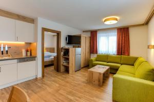 a living room with a green couch and a kitchen at Haus Bickel in Lech am Arlberg