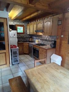 cocina con armarios de madera, mesa y nevera en Chalet Indépendant " L'anfian-ne", en Les Contamines-Montjoie