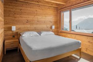 Ce lit se trouve dans une chambre en bois dotée d'une fenêtre. dans l'établissement Nachtigall OG, à Bettmeralp