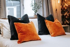 a bed with orange and black pillows on it at The Lighthouse, Boutique apartment in the town centre in Tavistock