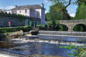 a river with a waterfall next to a bridge at The Lighthouse, Boutique apartment in the town centre in Tavistock