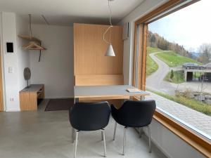 eine Küche mit einem Schreibtisch, 2 Stühlen und einem Fenster in der Unterkunft Bregenzerwaldblick in Schwarzenberg im Bregenzerwald