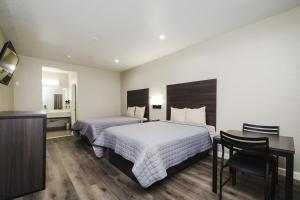 Habitación de hotel con 2 camas y escritorio en Winchester Inn and Suites Humble/IAH/North Houston, en Humble