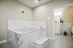 a white bathroom with a tub and a toilet at Winchester Inn and Suites Humble/IAH/North Houston in Humble