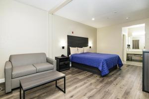 a hotel room with a bed and a chair at Winchester Inn and Suites Humble/IAH/North Houston in Humble