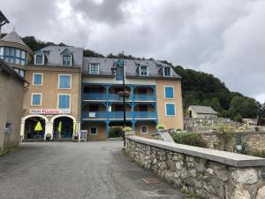 a large building with a stone wall in front of it at Appartement 3è étage à St-Marie-de-Campan in Sainte-Marie-de-Campan
