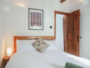 a bedroom with a white bed with a wooden headboard at Welcome Cottage in Woolfardisworthy