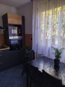 eine Küche mit einem Tisch, einer Mikrowelle und einem Fenster in der Unterkunft Pihenő Zug Apartman in Budapest