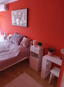 Schlafzimmer mit roten Wänden, einem Bett und einem Tisch in der Unterkunft Pihenő Zug Apartman in Budapest