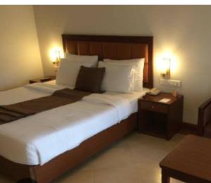 a large bed in a hotel room with two lamps at Royal Suites kangarappady in Cochin