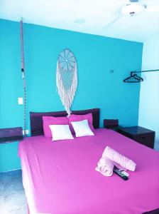 sypialnia z różowym łóżkiem z dwoma pilotami w obiekcie Costa Esmeralda w mieście El Cuyo