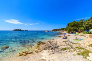 a beach with people laying on the sand and the water at Al Mare Apartments in Rovinj