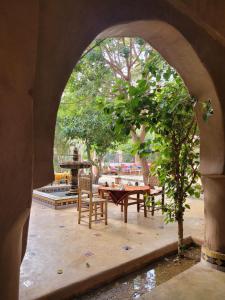 un arco che conduce a un patio con tavolo e sedie di Riad Tabhirte a Agdz