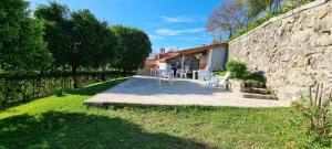 a patio with a table and chairs next to a stone wall at Casa de Férias V6 com piscina in Ponte de Lima