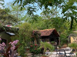 einen Garten mit einem Gebäude mit Stühlen und Blumen in der Unterkunft Casas del Toro Playa Flamingo in Playa Flamingo