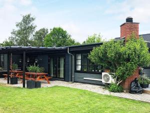 una casa negra con una mesa de picnic en un patio en Holiday home Gilleleje LXXV en Gilleleje