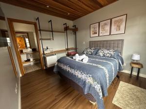 ein Schlafzimmer mit einem Bett mit einer blauen Decke in der Unterkunft Suítes Paz na Montanha - Tesouro Escondido in Campos do Jordão
