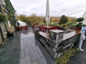 un patio con mesas, sillas y una sombrilla en The Beeches Holiday Home- based at Aberdunant Hall Holiday Park, en Prenteg