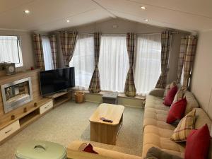 a living room with a couch and a tv at The Beeches Holiday Home- based at Aberdunant Hall Holiday Park in Prenteg