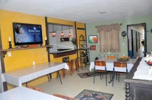 uma cozinha e sala de jantar com uma mesa e uma televisão em ANGEL'S SEA Pousada em Rio das Ostras