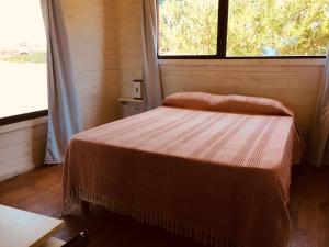 a small bedroom with a bed and a window at Cabañas Utopía in Punta Del Diablo
