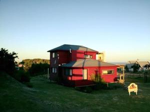 uma casa vermelha com um telhado preto num quintal em Cabañas Utopía em Punta Del Diablo