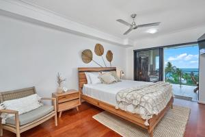 a bedroom with a bed and a chair and a window at Stunning 2-3 Bed Penthouse Glorious Ocean Views in Trinity Beach