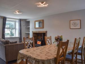 a dining room with a table and chairs and a fireplace at Llwyn Yr Arth in Llanbabo