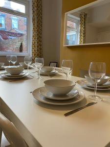 a table with plates and wine glasses on it at Thornton - Stylish 3 bed terraced house with free parking in Darlington