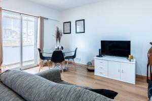 uma sala de estar com um sofá, uma televisão e uma mesa em Faro Center with AC & WiFi em Faro