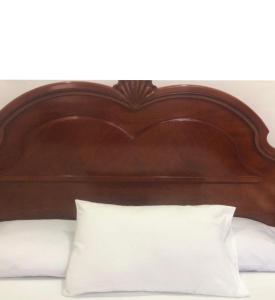 1 cama con cabecero de madera y almohada blanca en Hotel CALLI YOLOTL Teotihuacan, en San Juan Teotihuacán