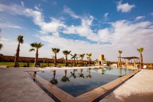 a swimming pool with palm trees and a sky at Aghmat Lodge Guest house in Marrakesh