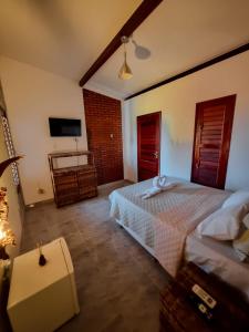 sypialnia z białym łóżkiem i telewizorem w obiekcie Aloha Beach Guest House w mieście Maragogi