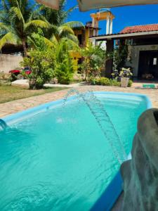 a swimming pool with a water fountain in front of a house at Aloha Beach Guest House in Maragogi