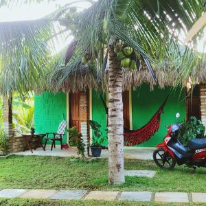 a motorcycle parked in front of a house with a palm tree at Vila Coqueiro - Moitas in Amontada