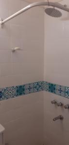 y baño con ducha y azulejos azules y blancos. en Monoambiente en Caballito para 2 personas en Buenos Aires