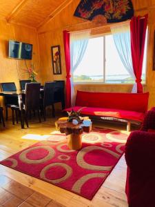 sala de estar con sofá rojo y alfombra roja en Cabañas Agroturismo Pupelde, en Ancud