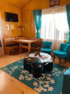 sala de estar con mesa y sillas azules en Cabañas Agroturismo Pupelde, en Ancud