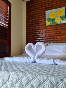 Aloha Beach Guest House في ماراغوغي: زوج من البجعات تشكيل قلب على سرير