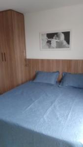 een bed met blauwe lakens en blauwe kussens bij Flat Constelações in Campos dos Goytacazes