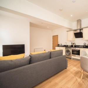 ノッティンガムにあるMarlborough Hall Majestic Apartment - Quietのリビングルーム(グレーのソファ付)、キッチンが備わります。