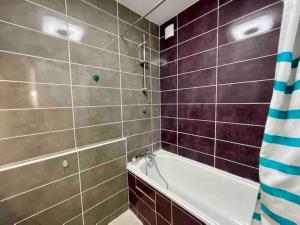La salle de bains est pourvue d'une baignoire blanche et de murs carrelés bruns. dans l'établissement Friendly Bean, à Cachan