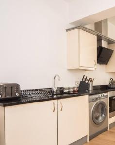 a kitchen with a sink and a washing machine at Marlborough Hall Majestic Apartment - Quiet in Nottingham