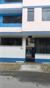 un edificio azul y blanco con ventanas de barrica negra en Huayqui, en Lima