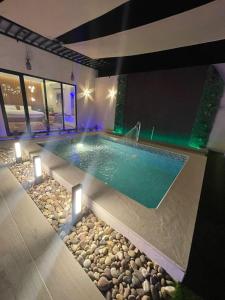una piscina en una casa con luces y rocas en شاليه ريفو Revo chalet, en Al-Hasa