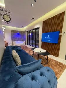 sala de estar con sofá azul y TV en شاليه ريفو Revo chalet en Al Ahsa